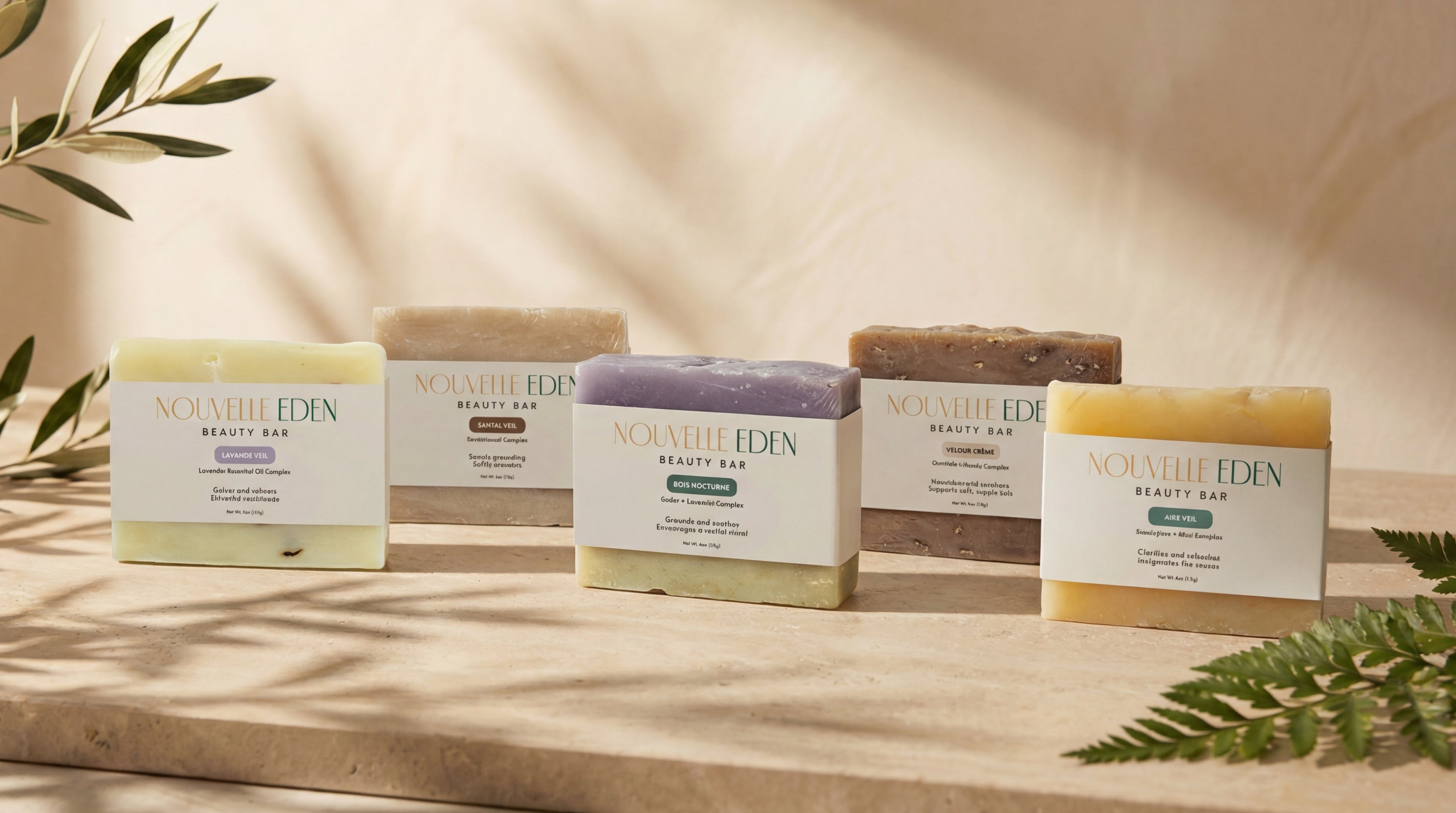 Collection of natural soap bars and boxes on a wooden surface with greenery.