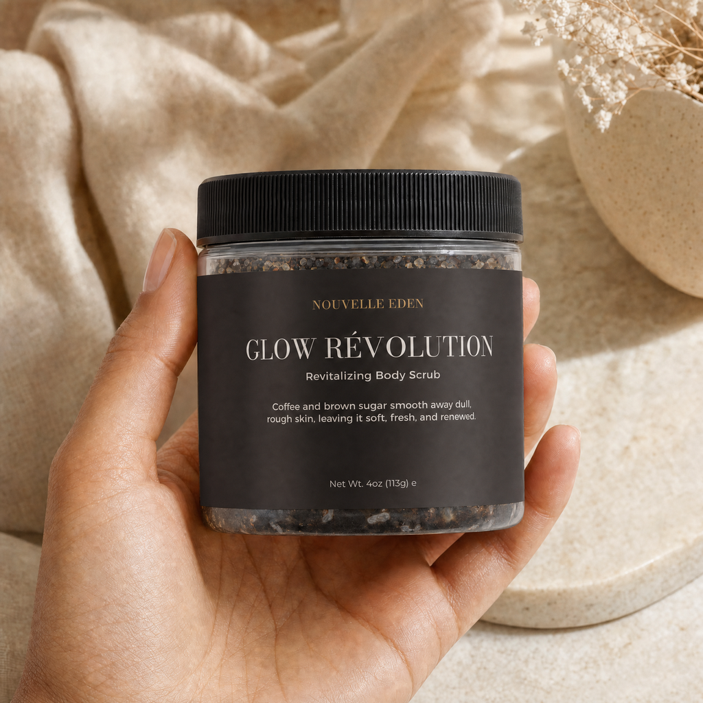 A hand holds a jar of Nouvelle Eden Glow Révolution Revitalizing Body Scrub, featuring a black label and black lid, set against a neutral background of beige fabric and a ceramic dish.